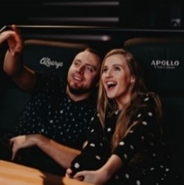 A man and a woman watch a movie in the cinema and rejoice, pointing a finger at what is happening.