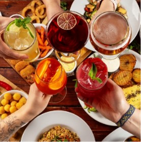 Five people, above the table with food, hold five different drinks.